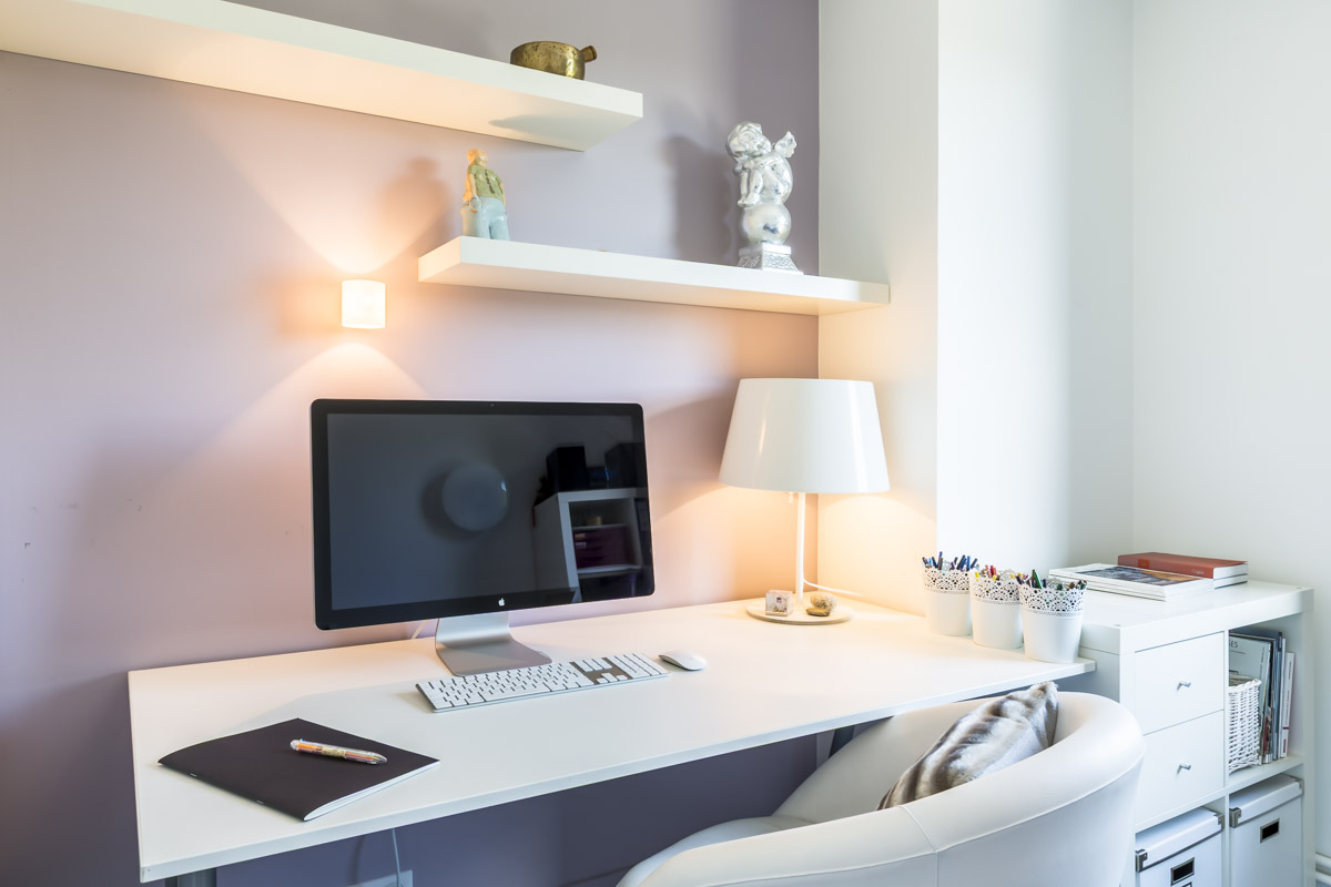 Un espace de travail soigné : ordinateur, lampe et étagères